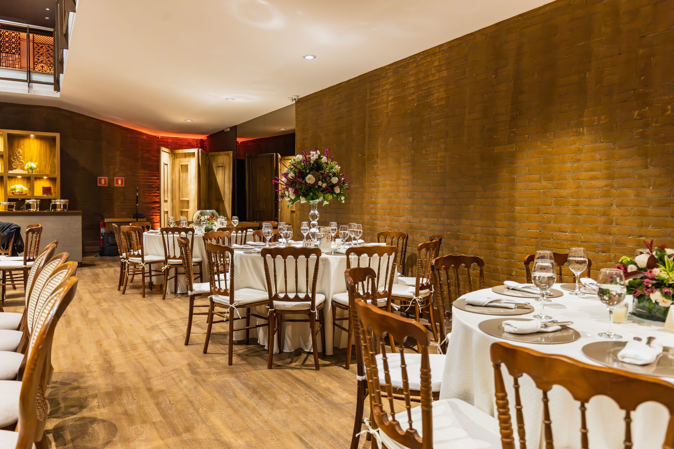 A beautifully decorated dining area set for a wedding reception with floral arrangements and fine tableware.