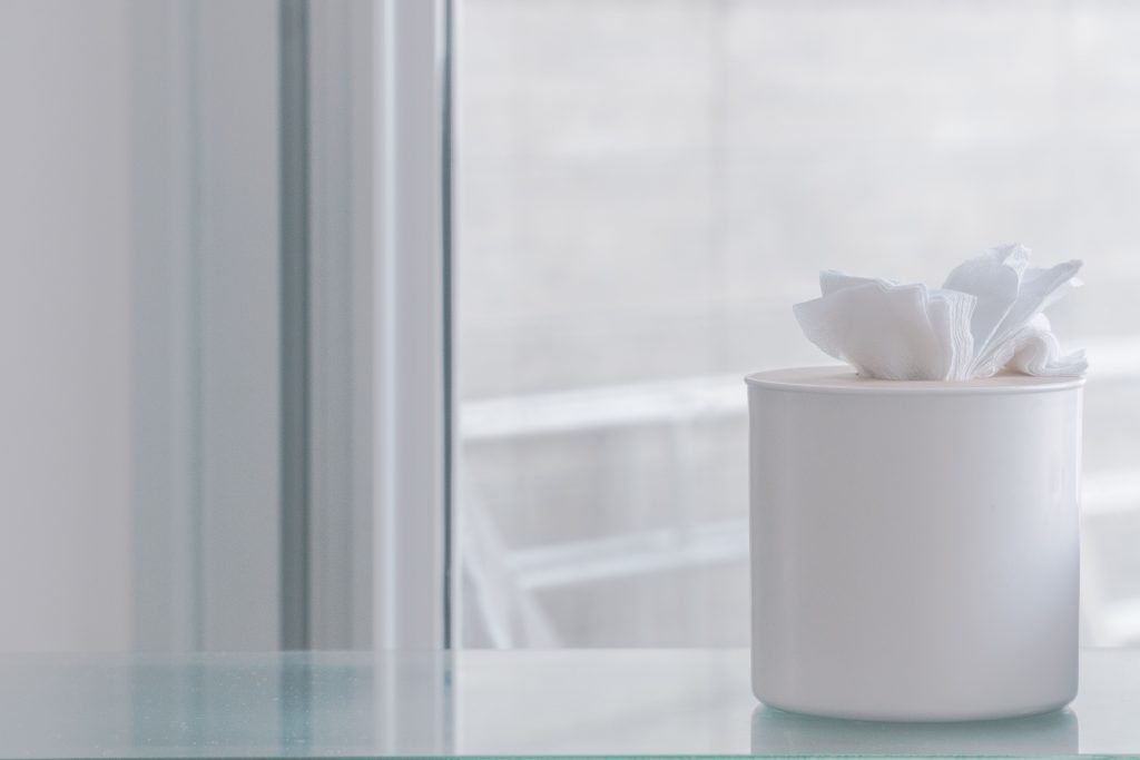 Elegant white tissue container on glass surface, evoking simplicity and minimalism.