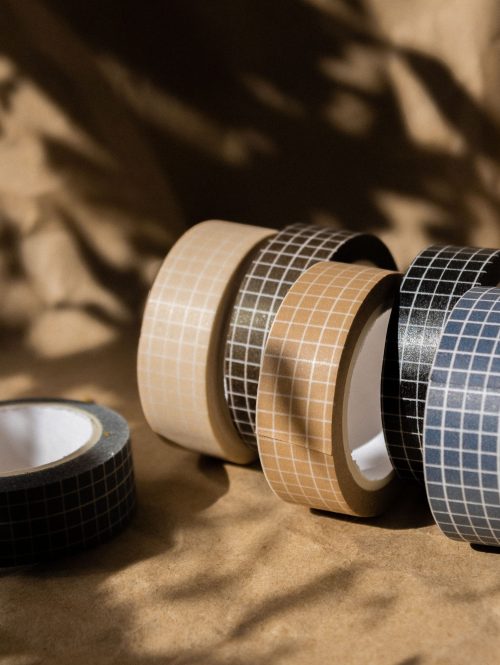 Aesthetic grid-patterned tapes arranged creatively with natural sunlight casting shadows.